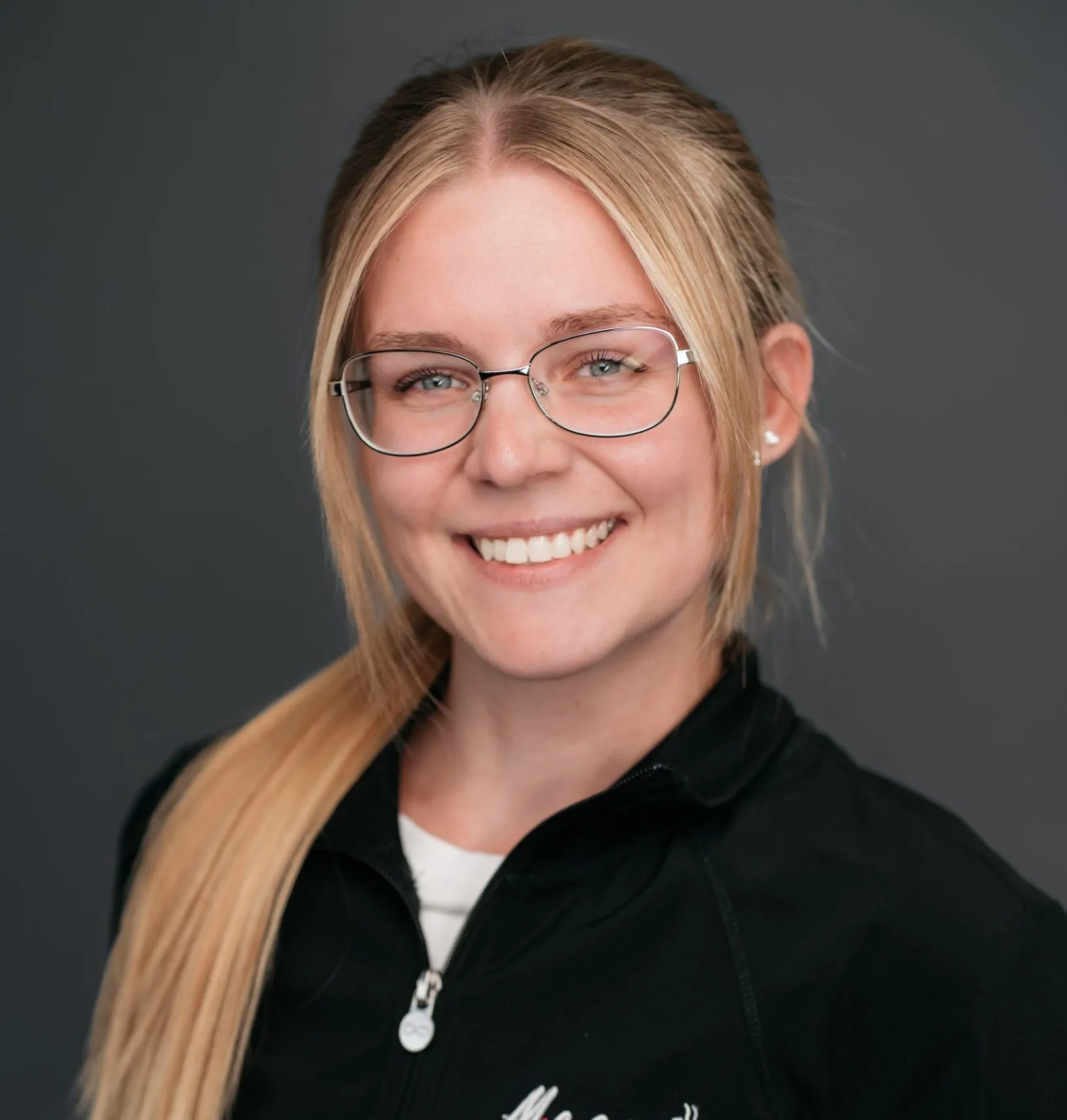Kayla, Masri Orthodontics team member, smiling and wearing glasses.
