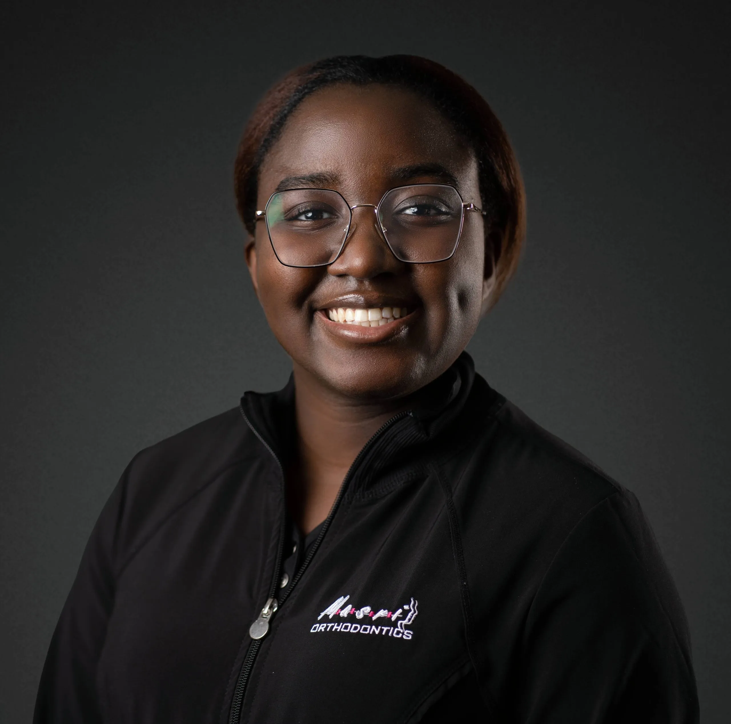 Reginae, Masri Orthodontics team member, smiling and wearing glasses.